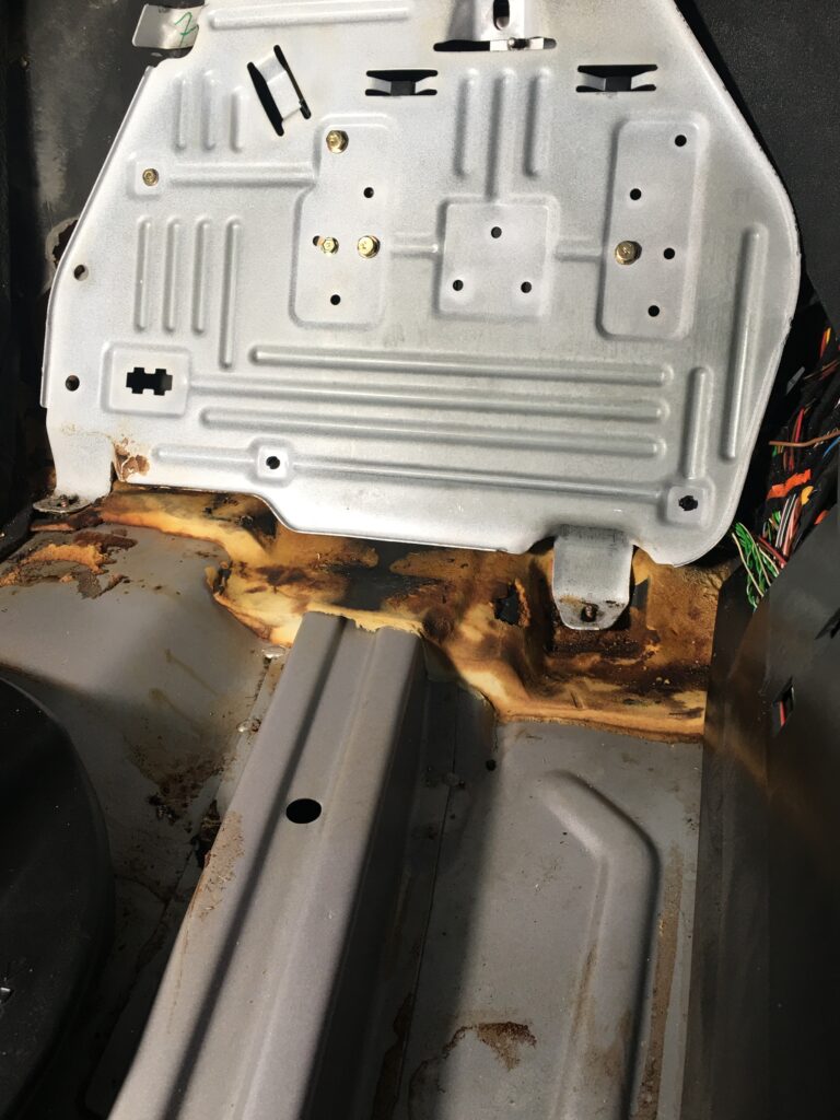 View of the metal floor pan of a 2001 Mercedes CLK with carpet removed, with TCM attached underneath.